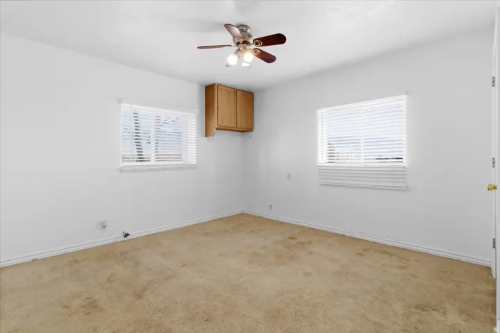Carpeted empty room featuring ceiling fan
