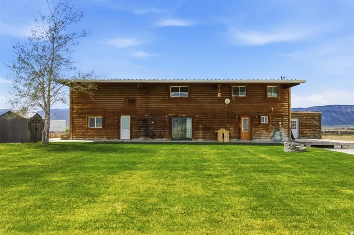 Rear view of property with a mountain view and a lawn