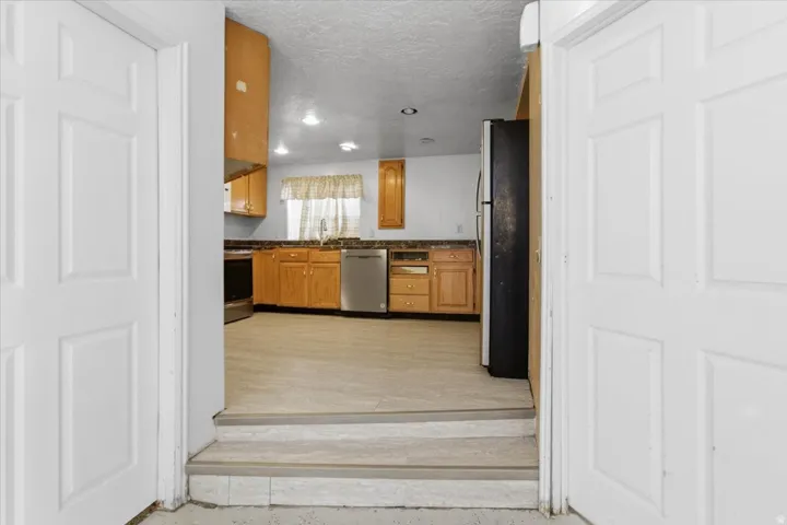 Kitchen featuring wood finish cabinetry, a textured ceiling, stainless steel appliances, and recessed lighting
