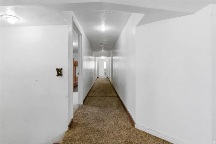Hallway with a textured ceiling and dark carpet