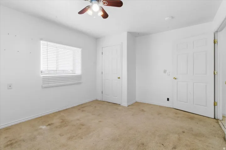 Unfurnished bedroom with light colored carpet and a ceiling fan