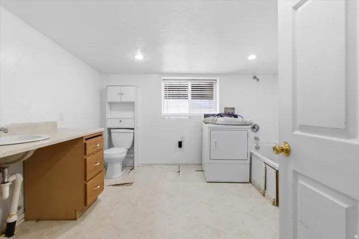 Full bath with washer / clothes dryer, light floors, vanity, recessed lighting, and a tub to relax in