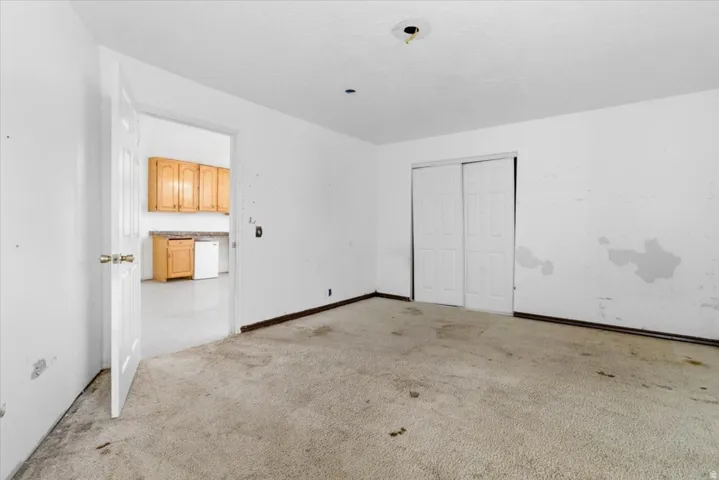 Unfurnished bedroom featuring light carpet and a closet
