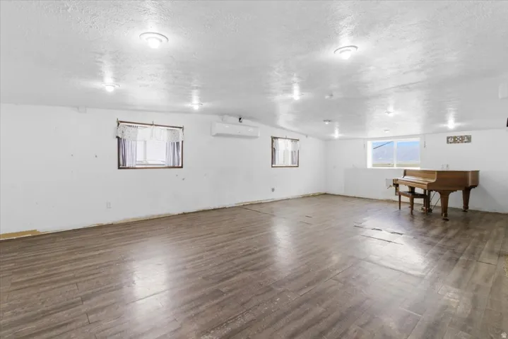 Basement featuring dark wood-type flooring, plenty of natural light, and a textured ceiling