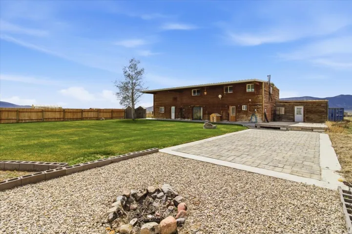 Rear view of house with a fire pit, a fenced backyard, a patio, a deck with mountain view, and faux log siding