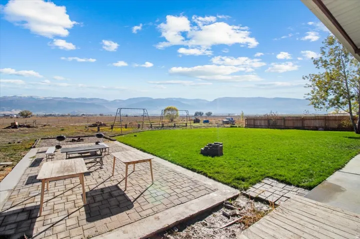 Fenced backyard with an outdoor fire pit, a patio, and a mountain view