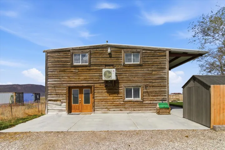 Rear view of property featuring a storage shed, log siding, and a patio