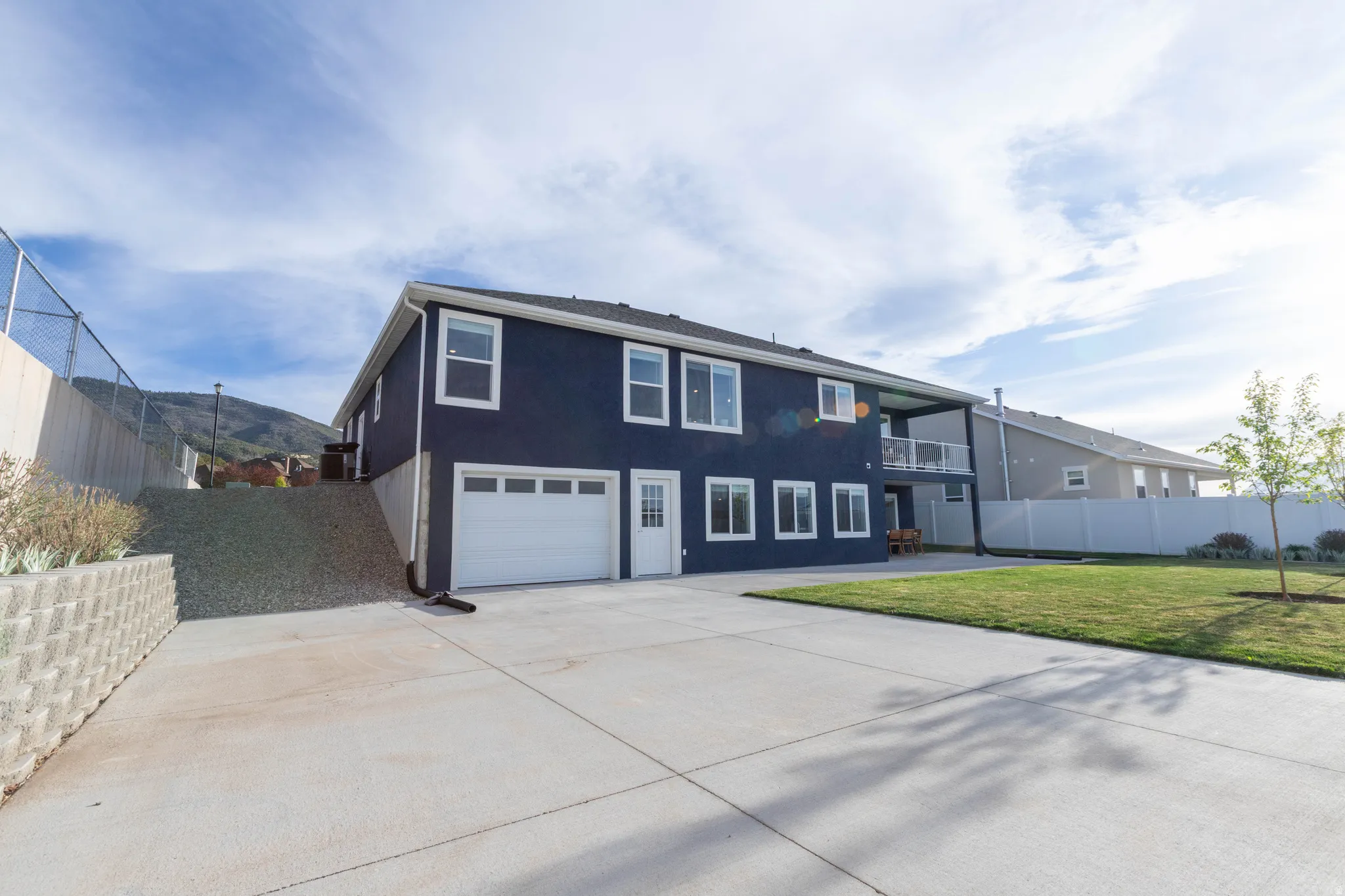 View of front of house with a garage, driveway, a balcony, and stucco siding