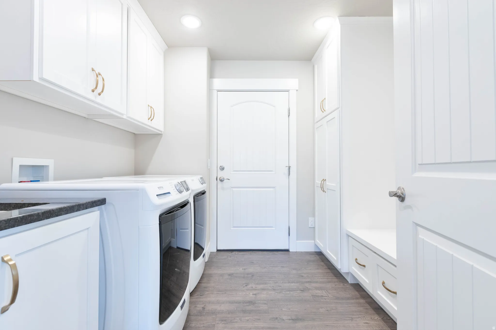 Laundry area with dark wood-style flooring, washer and dryer, cabinet space, and recessed lighting