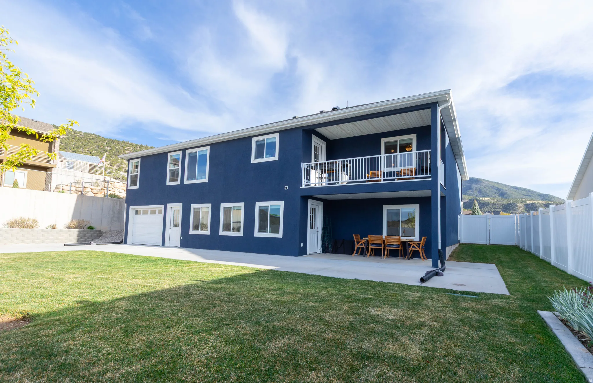 Rear view of property with a balcony, a fenced backyard, an attached garage, a patio area, and stucco siding