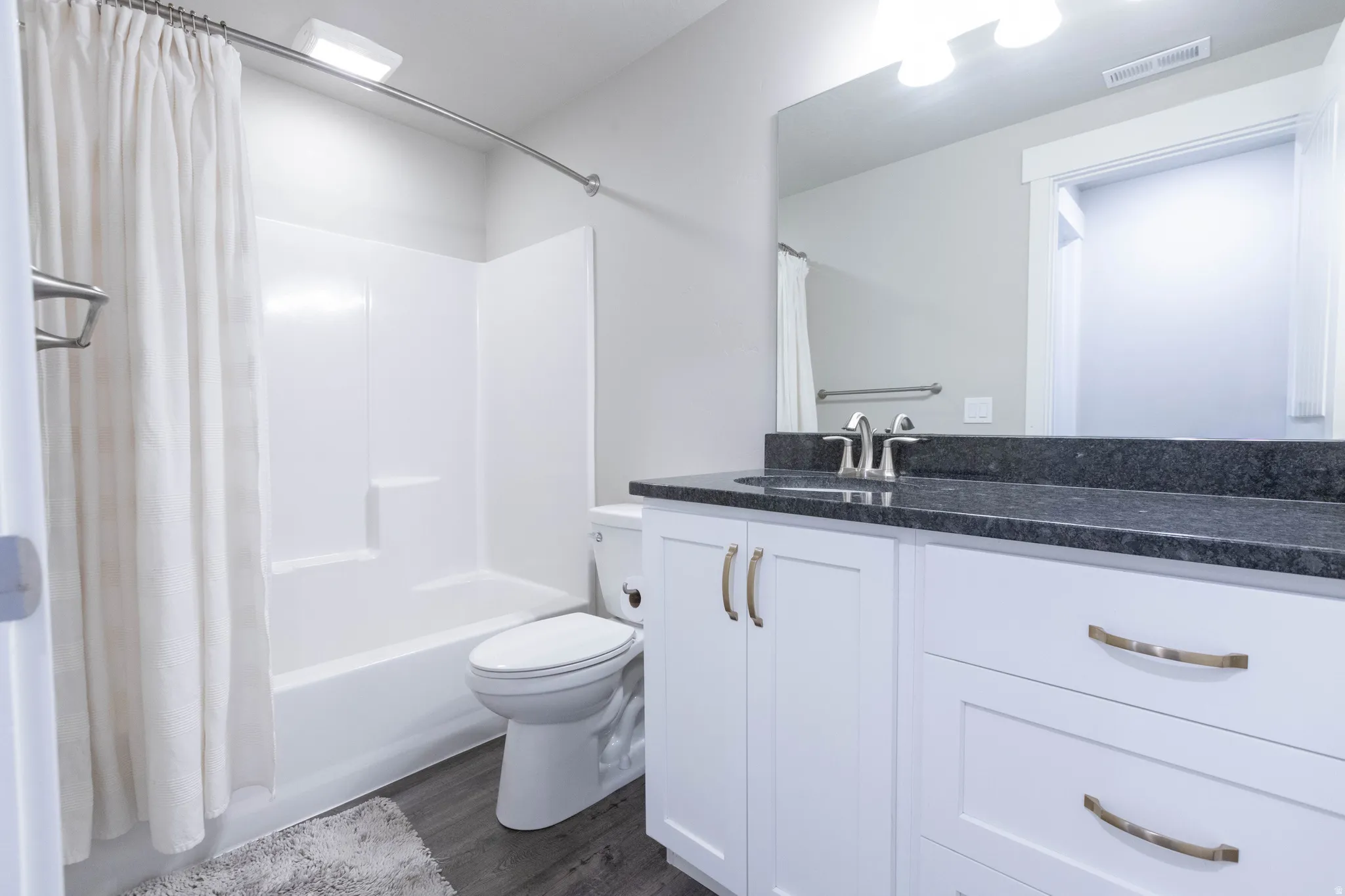 Bathroom featuring vanity, dark wood-style floors, and shower / bath combo