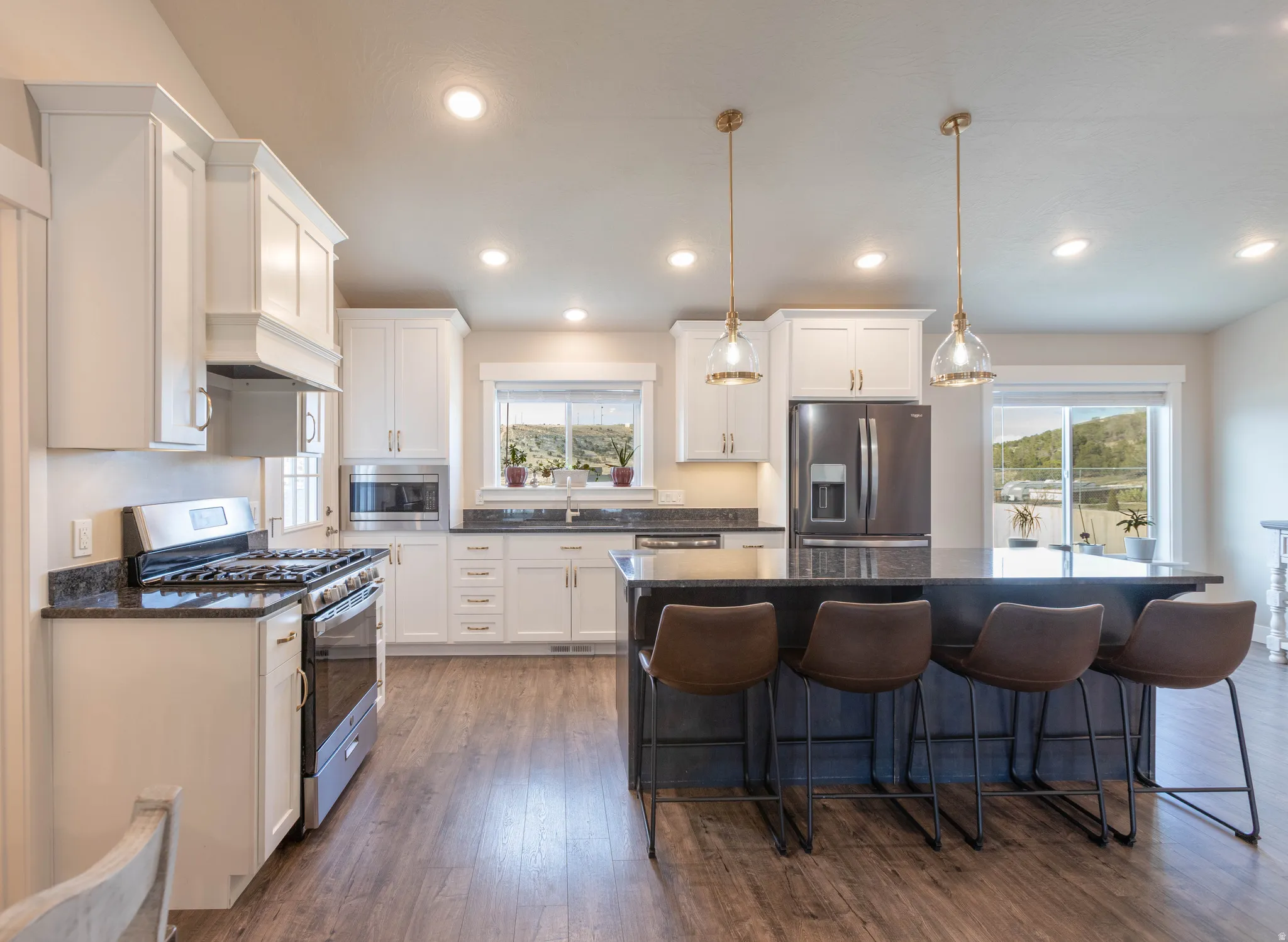 Kitchen featuring stainless steel appliances, a kitchen island, a kitchen breakfast bar, dark wood-style flooring, and dark stone countertops
