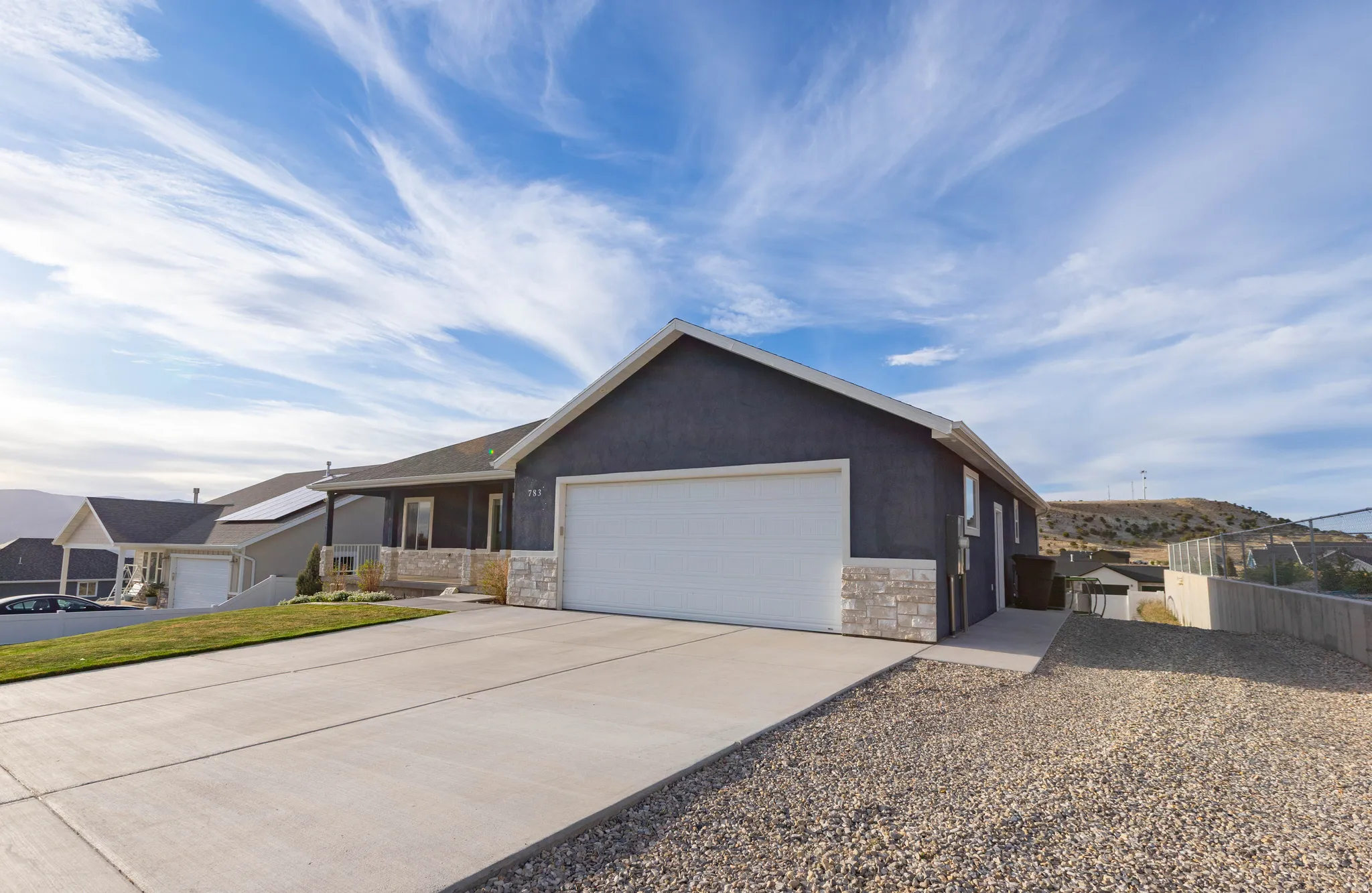 Single story home featuring stone siding, concrete driveway, a garage, a porch, and stucco siding