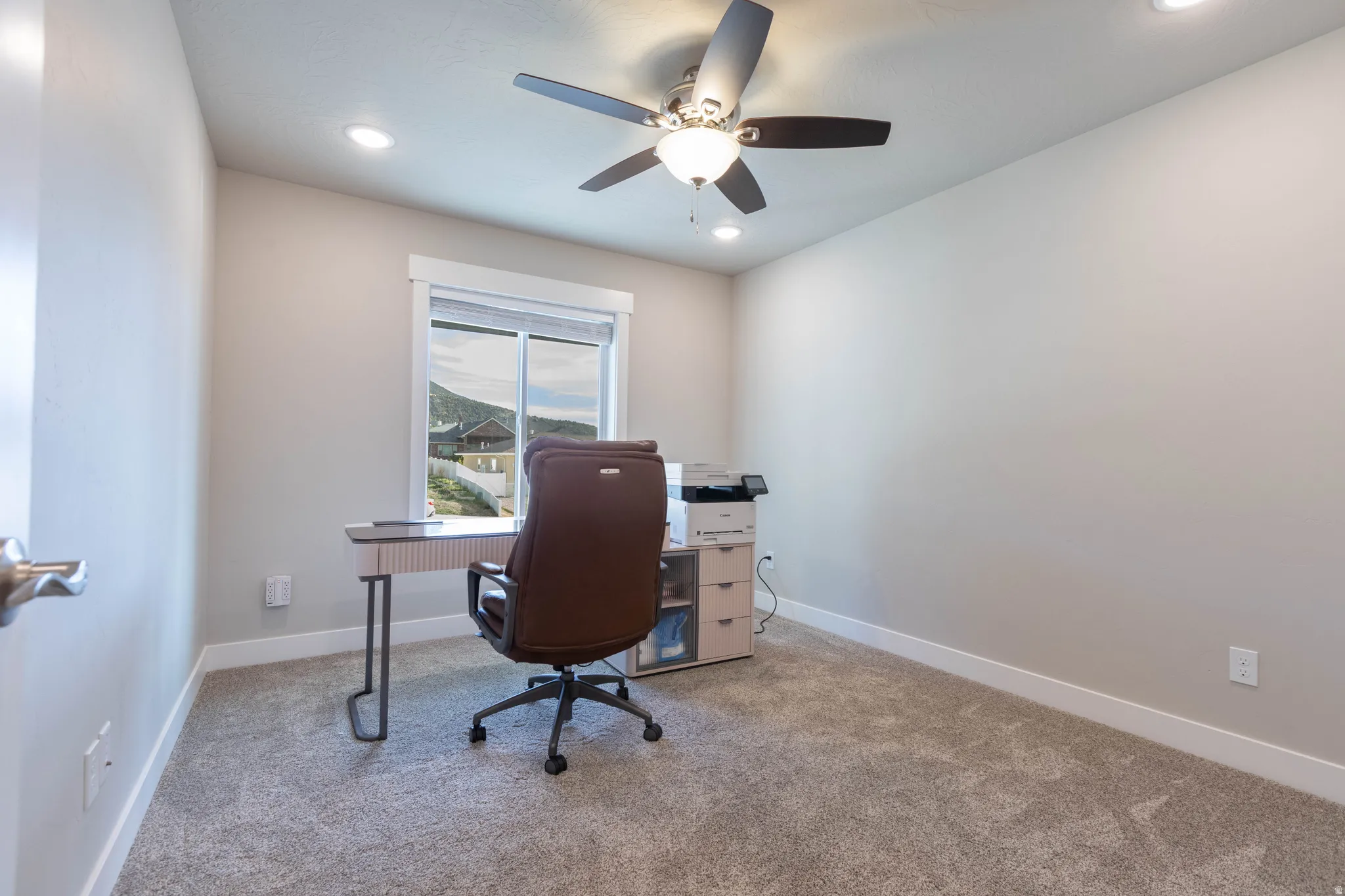 Office space featuring light colored carpet and a ceiling fan