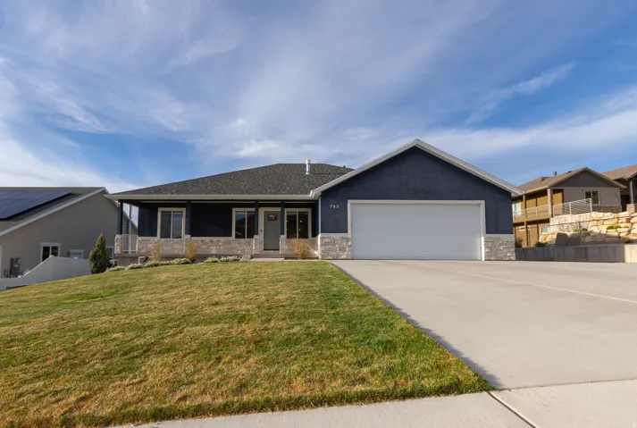 Single story home with stone siding, an attached garage, driveway, stucco siding, and a porch