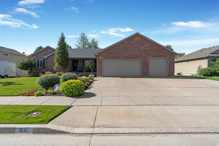Single story home featuring an attached garage, brick siding, driveway, and a front lawn