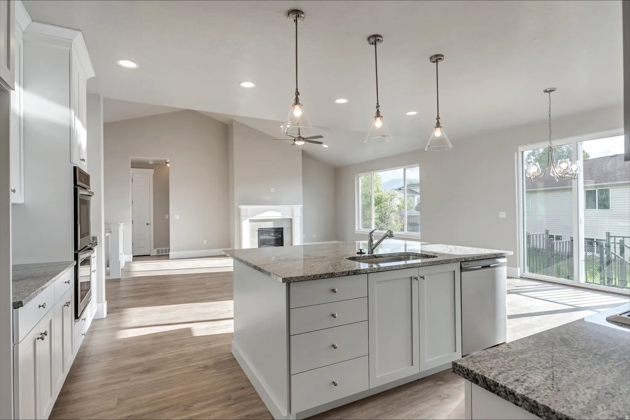 Kitchen featuring white cabinetry, a glass covered fireplace, dark stone countertops, ceiling fan, and lofted ceiling