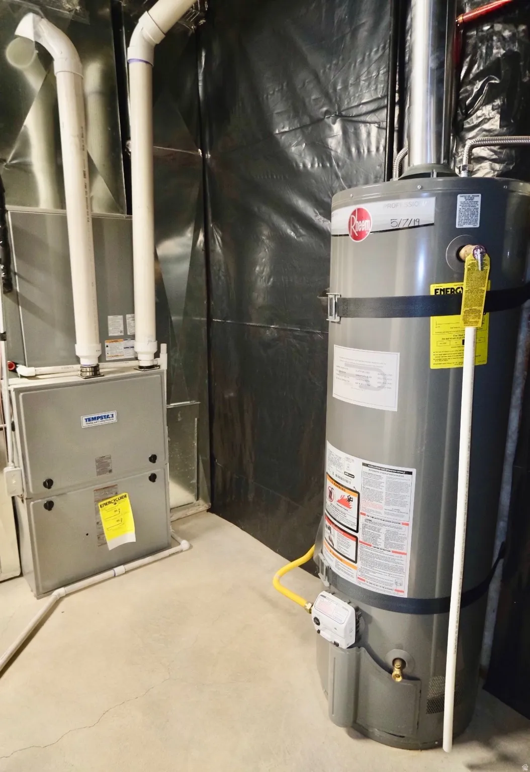 Utility room featuring secured 40-Gallon water heater and heating unit