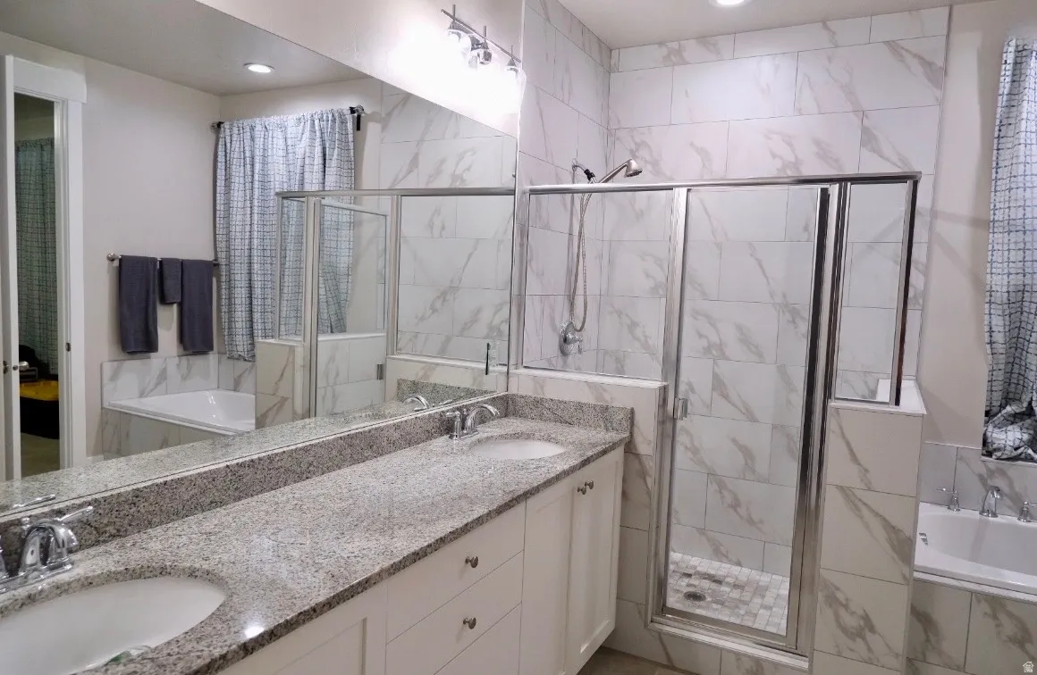 Full bath with a bath, double vanity, and a marble finish shower