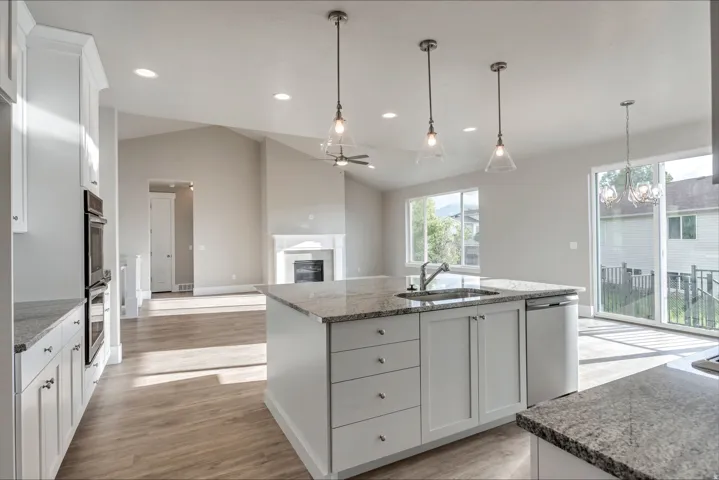 Kitchen featuring white cabinetry, a glass covered fireplace, dark stone countertops, ceiling fan, and lofted ceiling