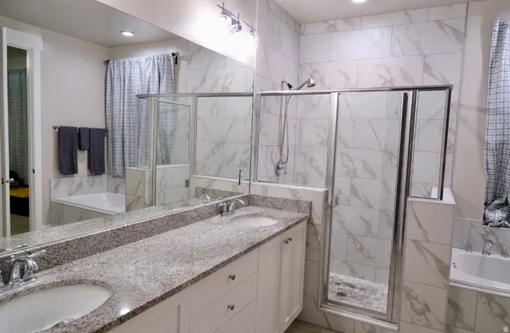 Full bath with a bath, double vanity, and a marble finish shower