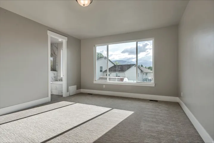 Unfurnished bedroom with light carpet and ensuite bath