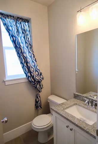 Half bathroom with vanity and dark tile patterned flooring