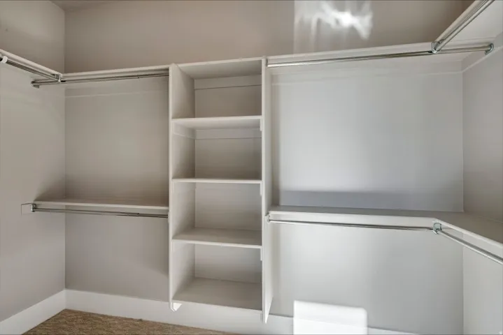Walk in closet featuring light colored carpet