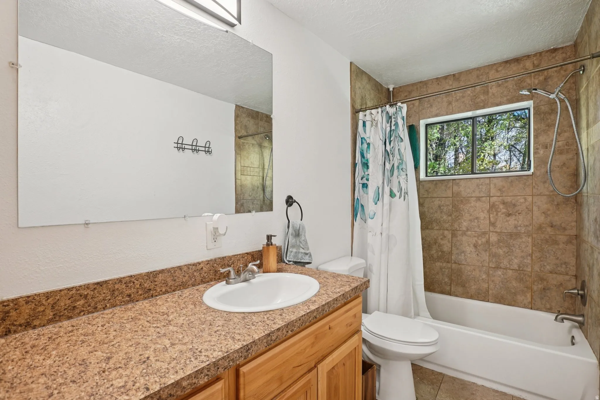 Full bathroom featuring vanity, shower / bath combo, a textured ceiling, and light tile patterned flooring