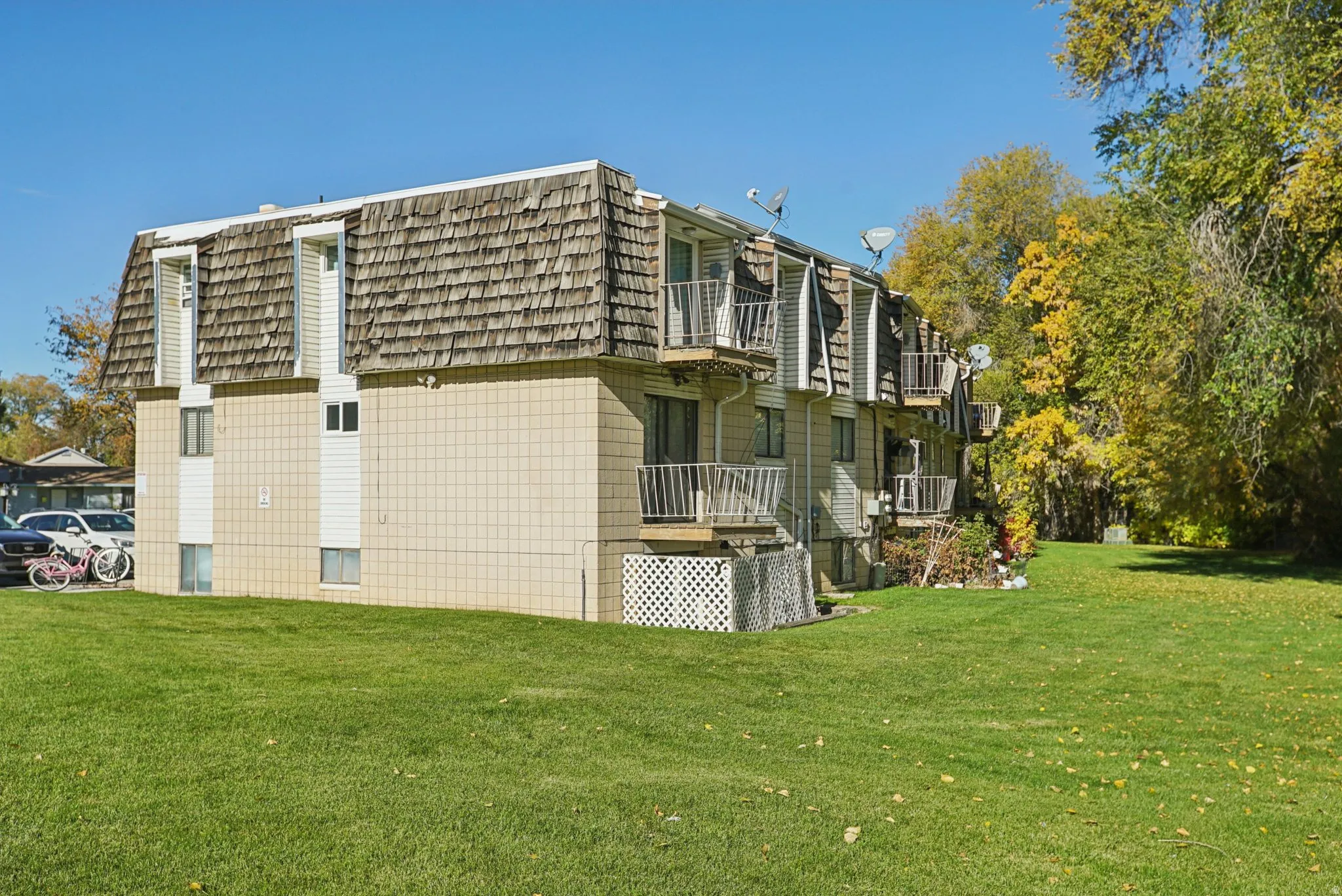 View of home's exterior with a balcony, mansard roof, and a yard