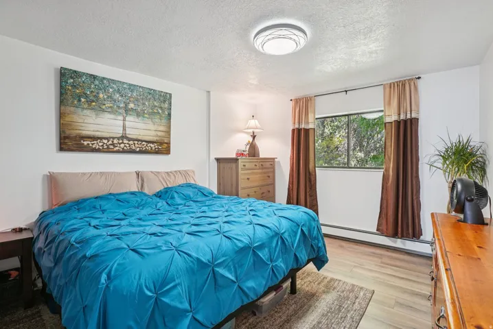 Bedroom featuring baseboard heating, a textured ceiling, and light wood-style flooring