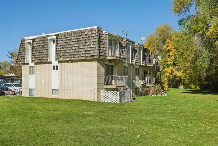 View of home's exterior with a balcony, mansard roof, and a yard