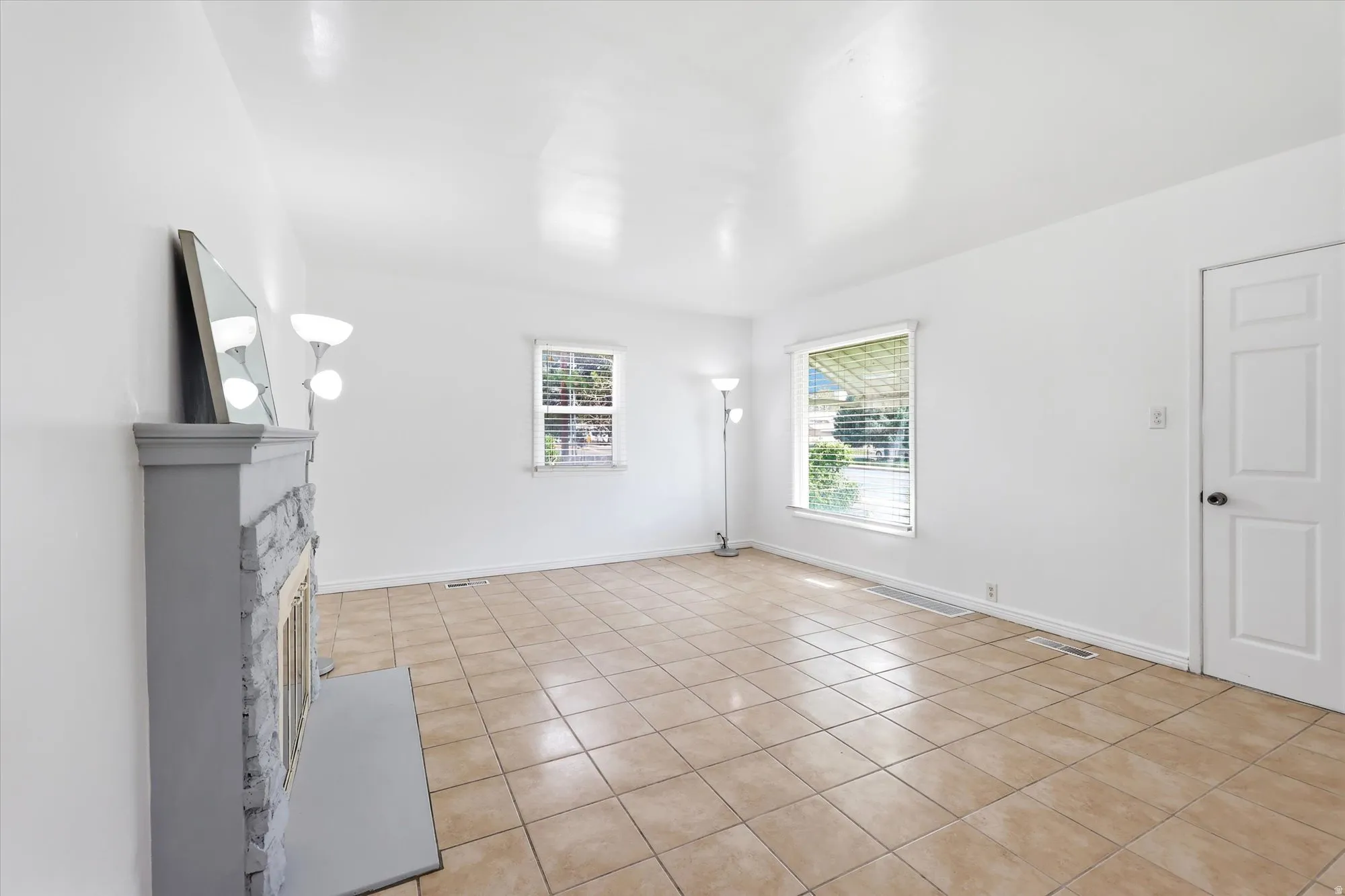 Unfurnished living room featuring light tile patterned floors and a fireplace