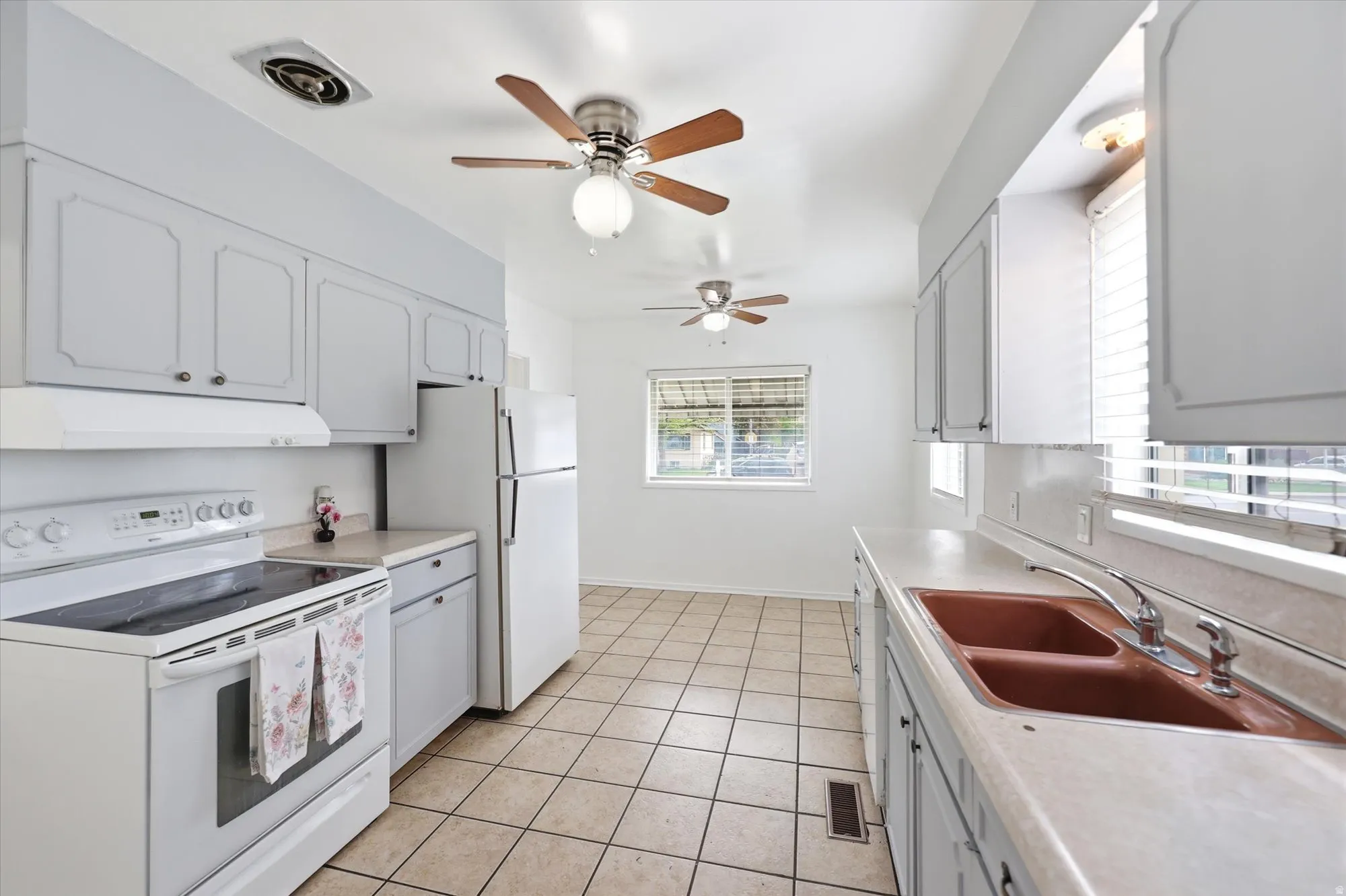 Kitchen featuring white appliances, light countertops, a ceiling fan, and light tile patterned flooring