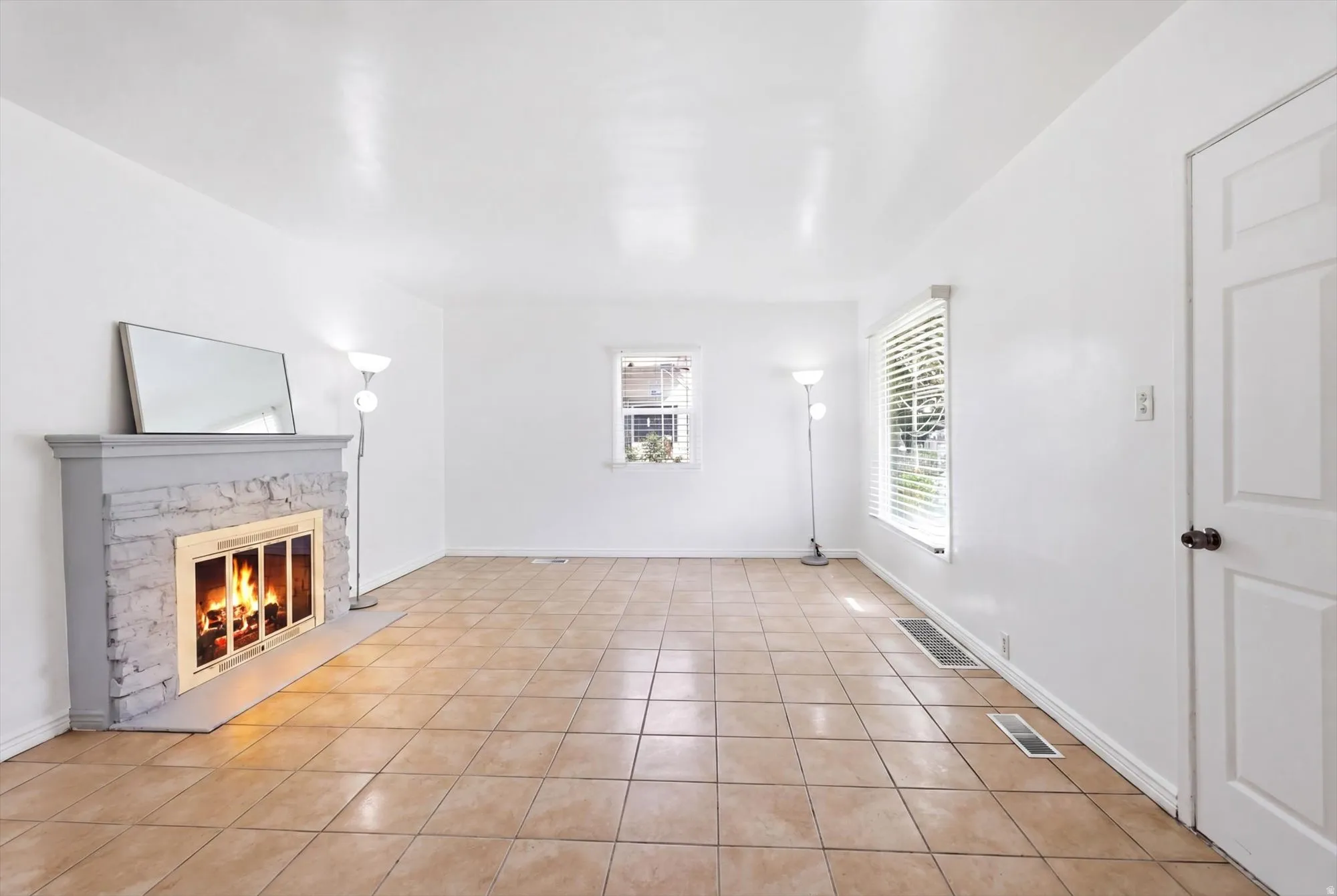 Unfurnished living room featuring a fireplace and light tile patterned flooring