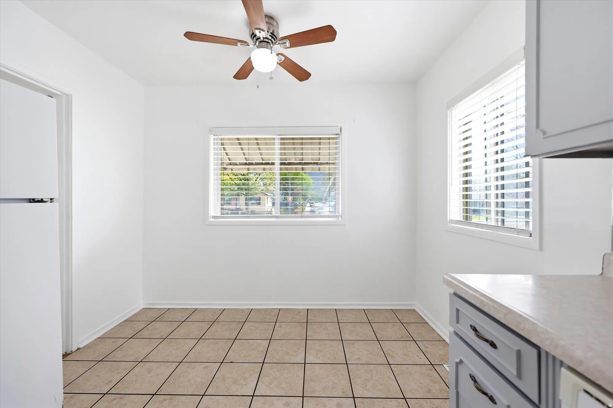 Unfurnished dining area featuring ceiling fan and light tile patterned floors