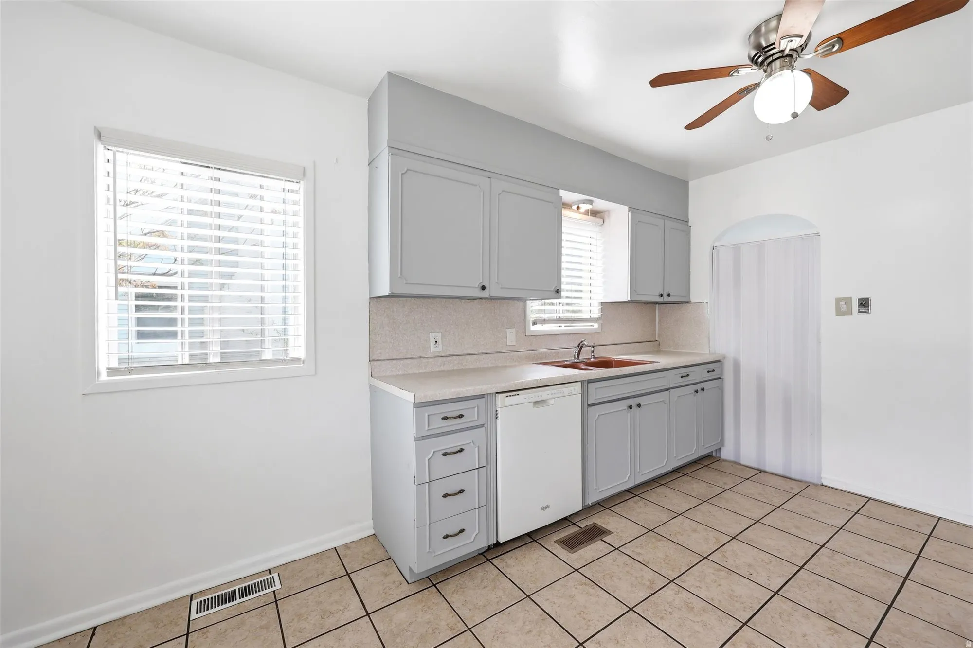 Kitchen featuring light countertops, ceiling fan, dishwasher, light tile patterned floors, and gray cabinetry