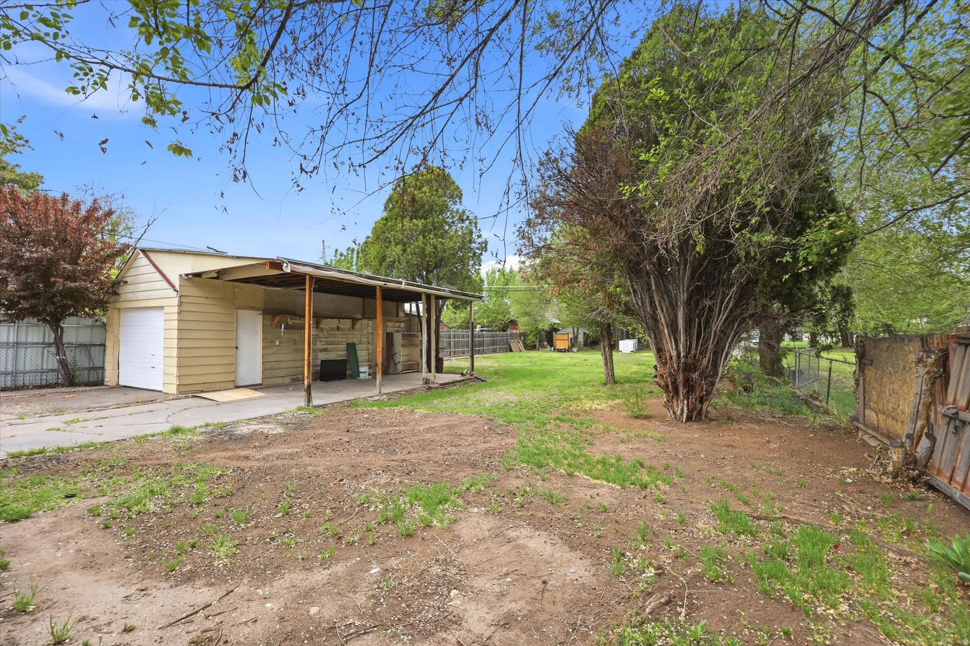 View of yard with an outdoor structure, a patio, a garage, and driveway