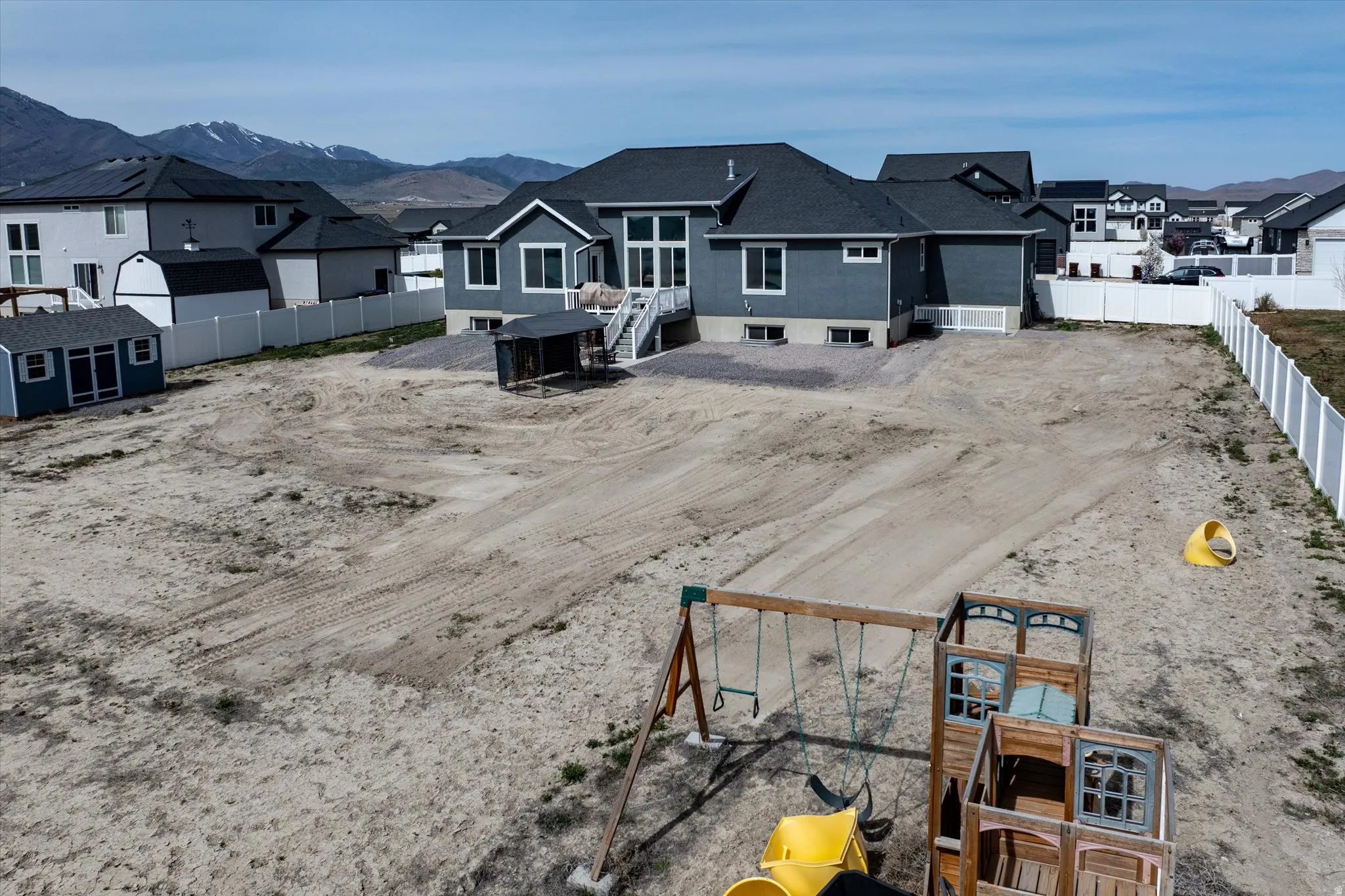 Rear view of house with a residential view, an attached garage, a fenced backyard, and a mountain view