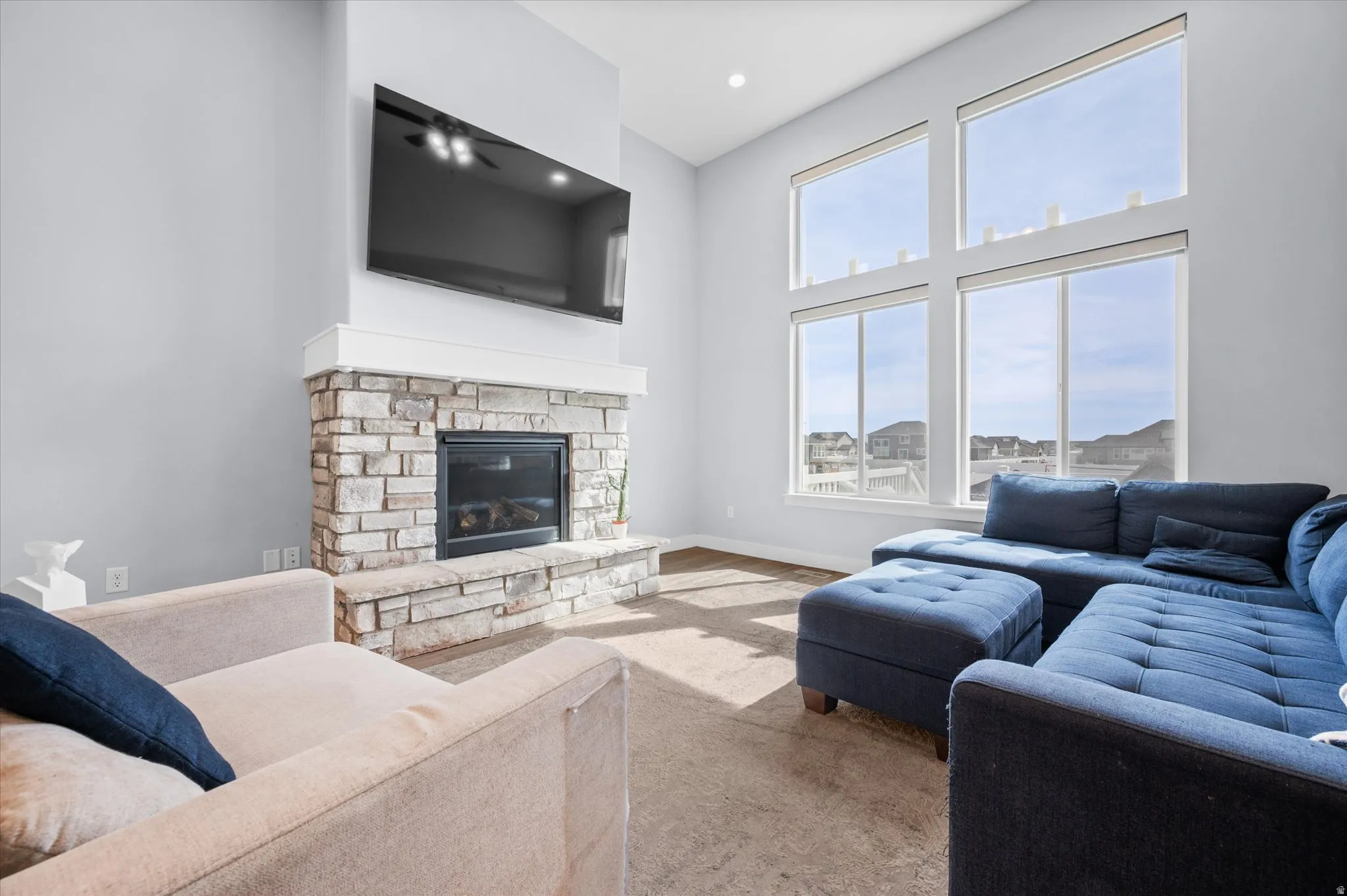 Living room featuring a stone fireplace, a cathedral ceiling, custom electric roller shades