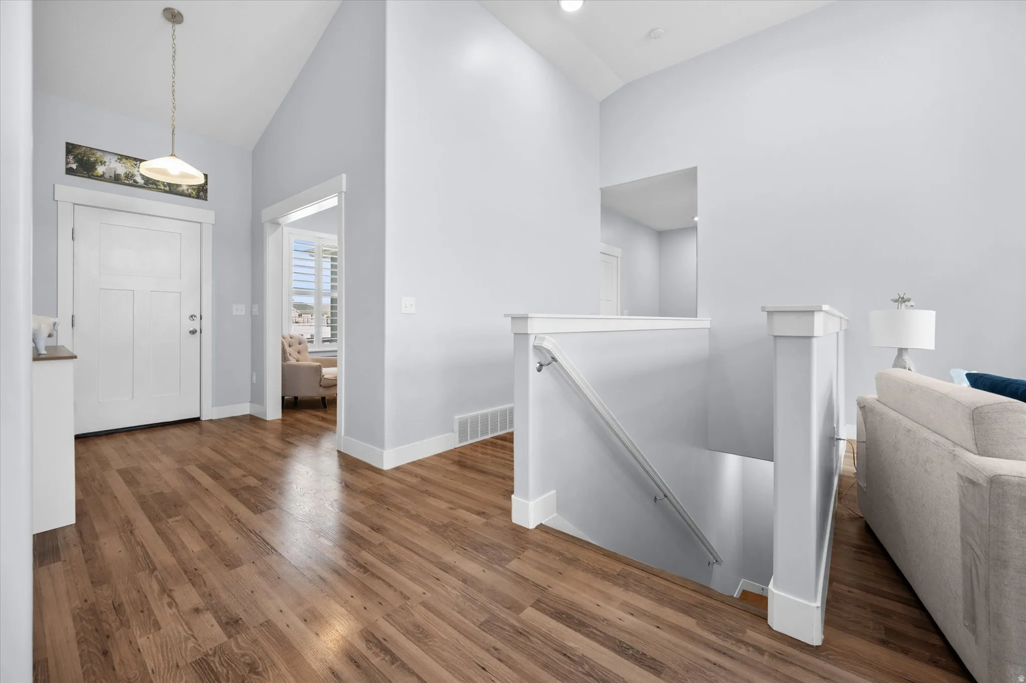 Open Foyer entrance featuring dark wood-style flooring and vaulted ceiling