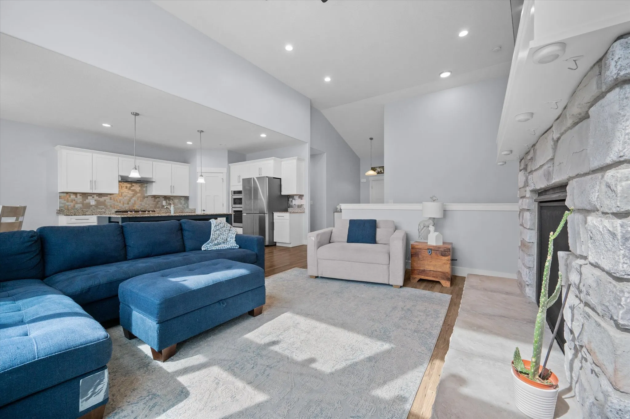 Living room featuring a fireplace, wood finished floors, recessed lighting, and lofted ceiling