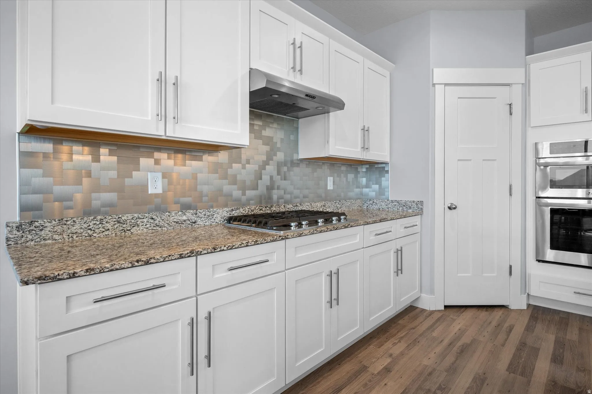 Kitchen featuring white cabinetry, light stone countertops, stainless steel appliances, and dark wood finished floors