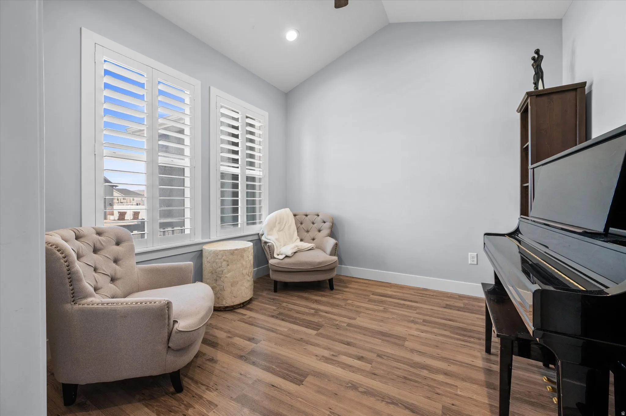 Sitting room with dark wood-style floors, lofted ceiling, custom shutters, and recessed lighting