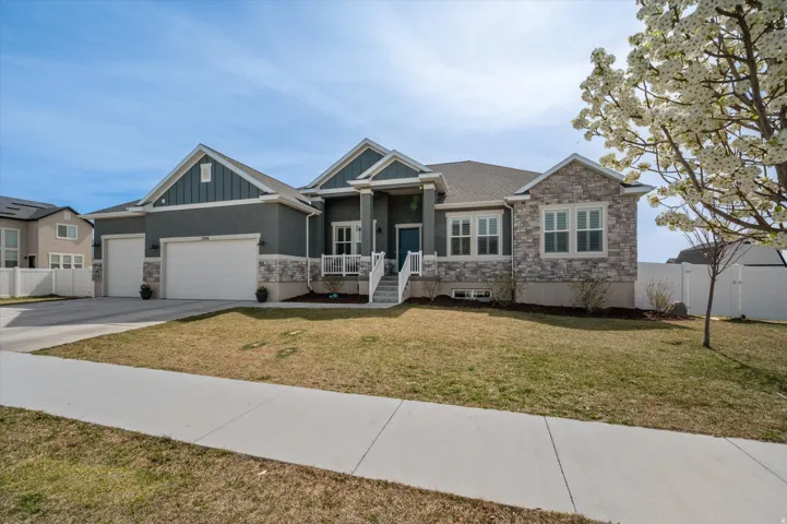 View of front of property with stone siding, a garage, concrete driveway, board and batten siding, and a porch