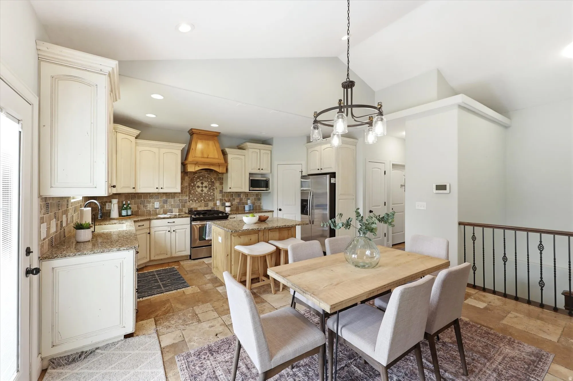 Dining room featuring lofted ceiling, stone tile floors, and a chandelier