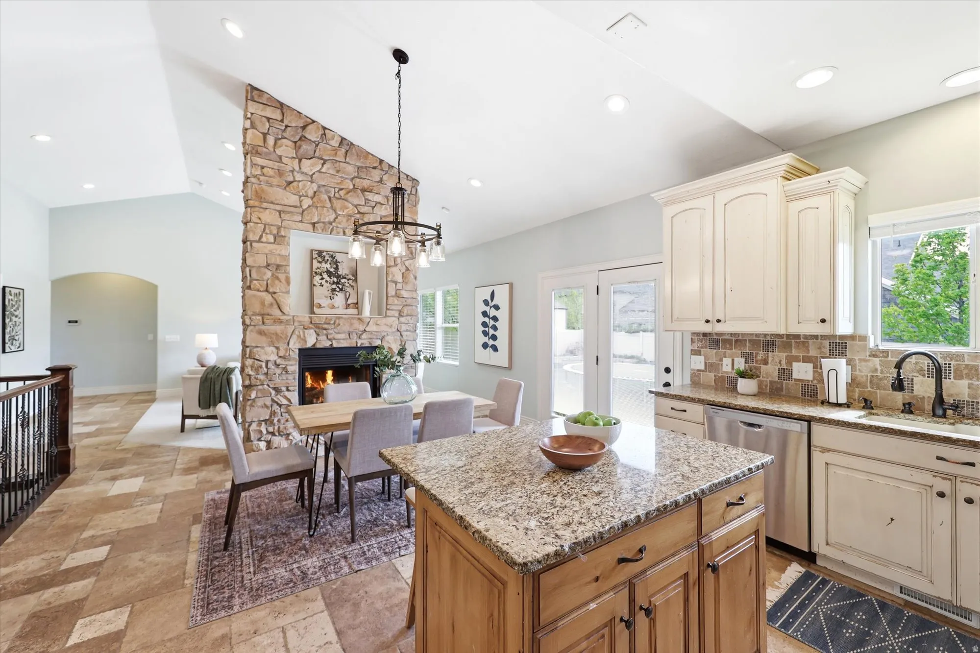 Kitchen featuring open floor plan, light stone countertops, stainless steel dishwasher, tasteful backsplash, and a center island
