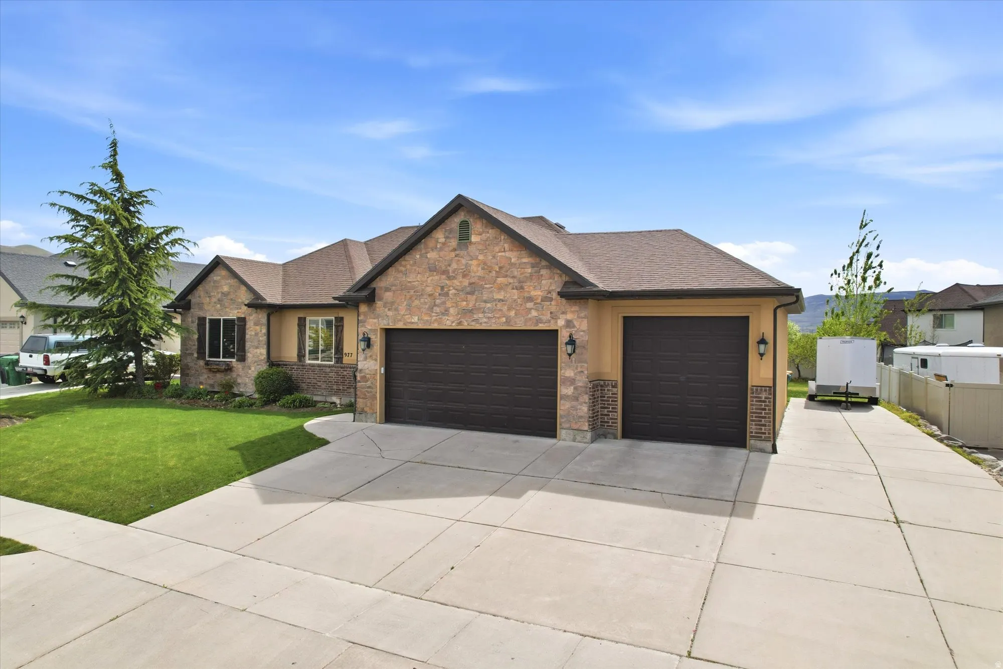 Craftsman-style house with an attached garage, driveway, stone siding, a front yard, and a shingled roof