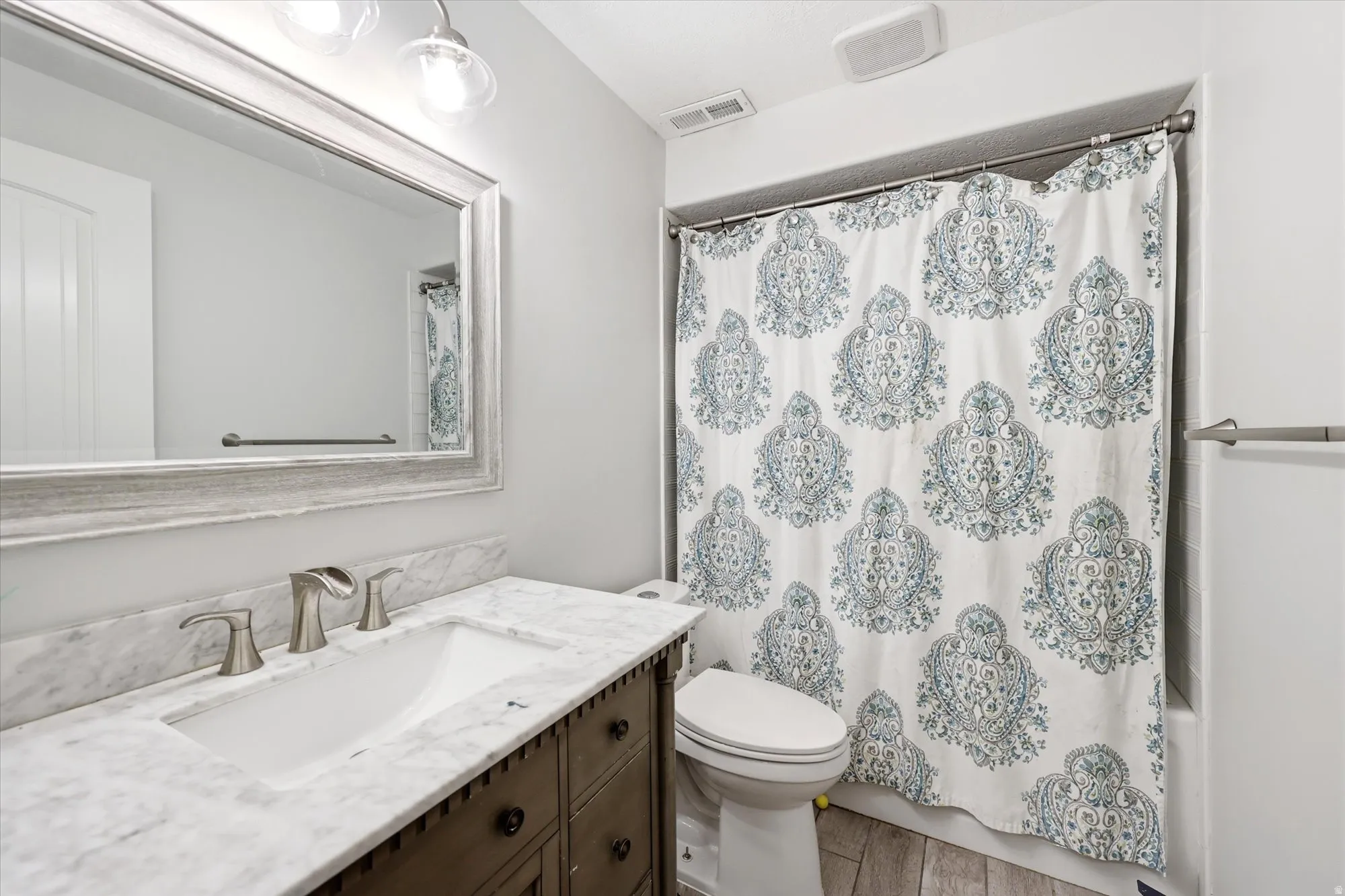 Full bathroom with vanity, shower / bath combination with curtain, and light wood-type flooring
