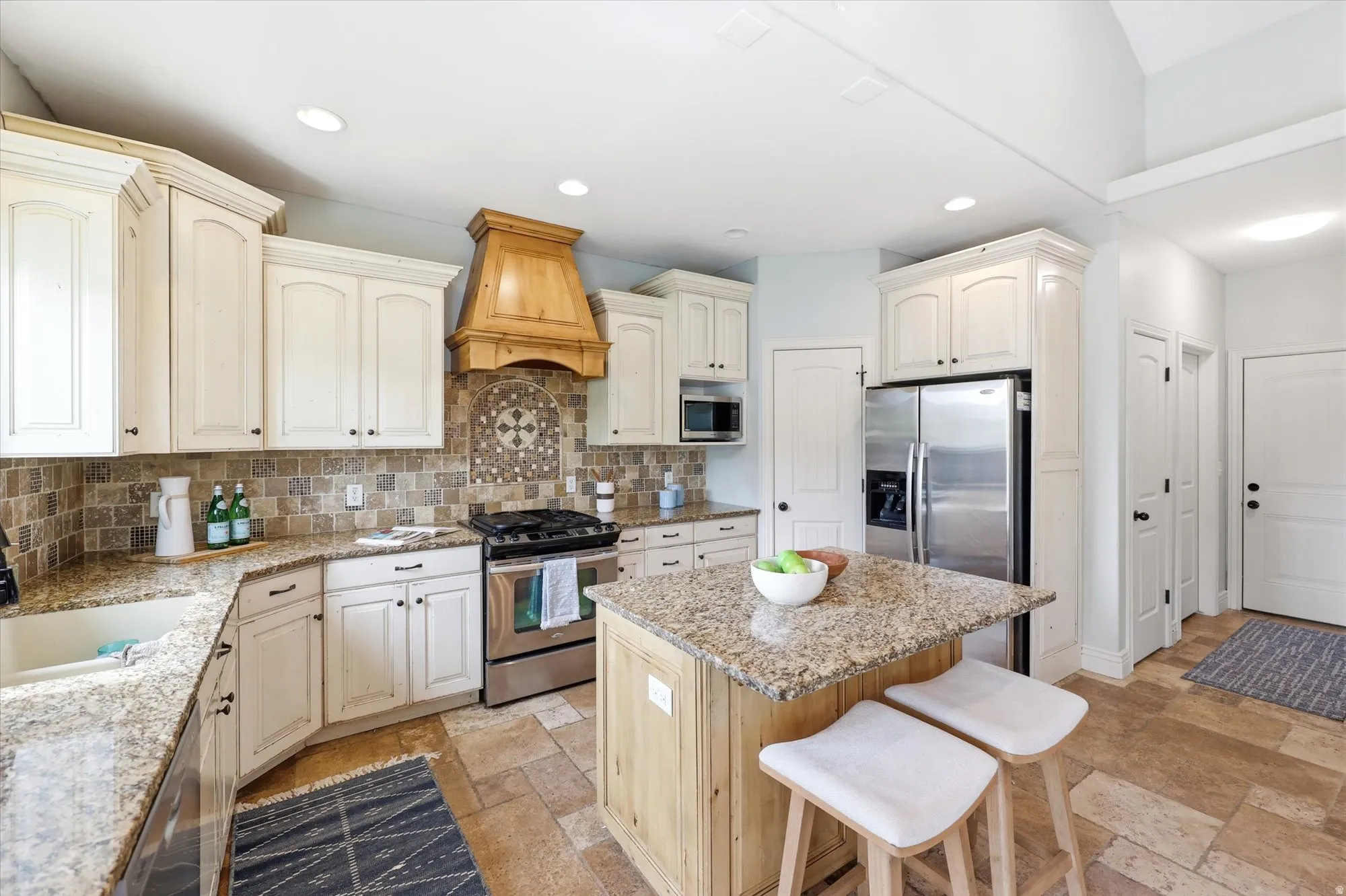 Kitchen featuring stainless steel appliances, light stone countertops, a breakfast bar, a kitchen island, and backsplash